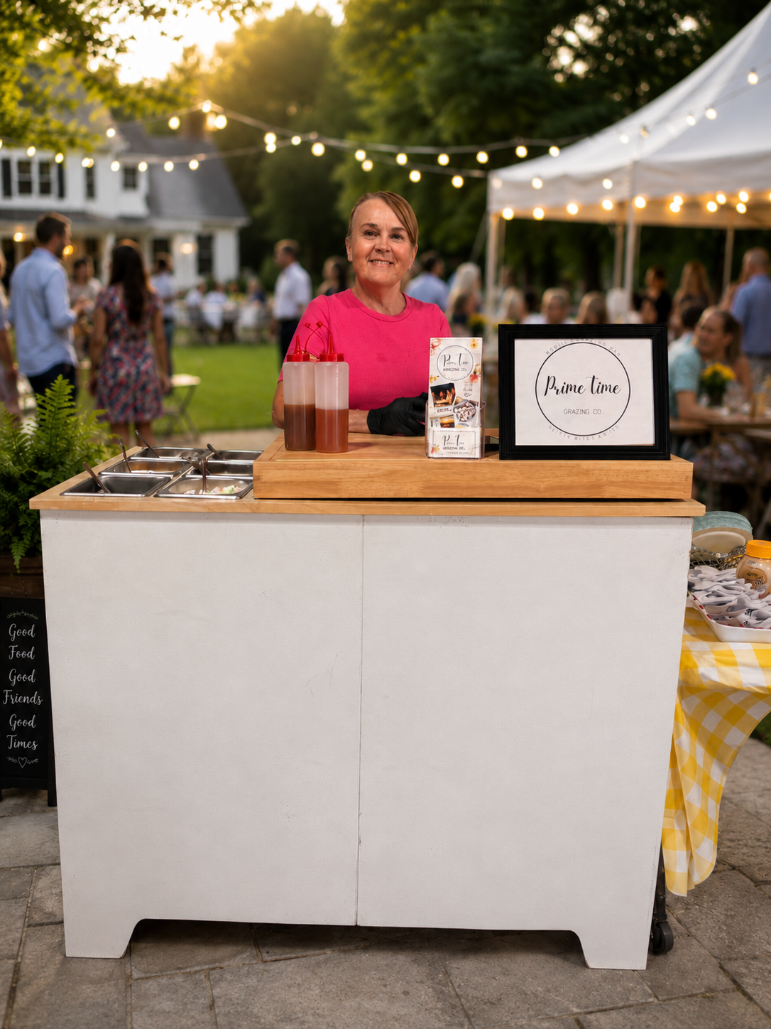 Christina serving guests at a Prime Time Grazing Co. mobile catering bar during an evening event